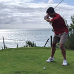 hitting from the tee on a golf course next to the sea