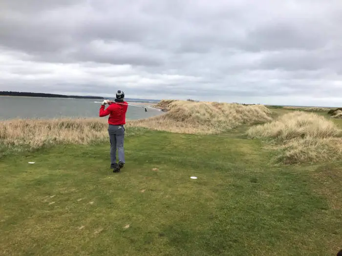 golfer teeing off on a links course in winter